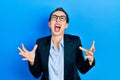 Young hispanic girl wearing business clothes and glasses crazy and mad shouting and yelling with aggressive expression and arms Royalty Free Stock Photo