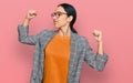 Young hispanic girl wearing business jacket and glasses showing arms muscles smiling proud Royalty Free Stock Photo