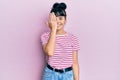 Young hispanic girl wearing casual clothes covering one eye with hand, confident smile on face and surprise emotion Royalty Free Stock Photo