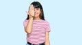 Young hispanic girl wearing casual clothes covering one eye with hand, confident smile on face and surprise emotion Royalty Free Stock Photo