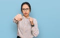 Young hispanic girl wearing casual clothes and glasses punching fist to fight, aggressive and angry attack, threat and violence Royalty Free Stock Photo