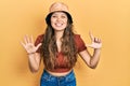 Young hispanic girl wearing casual clothes and hat showing and pointing up with fingers number seven while smiling confident and Royalty Free Stock Photo