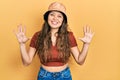 Young hispanic girl wearing casual clothes and hat showing and pointing up with fingers number ten while smiling confident and Royalty Free Stock Photo