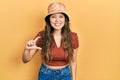 Young hispanic girl wearing casual clothes and hat smiling and confident gesturing with hand doing small size sign with fingers Royalty Free Stock Photo