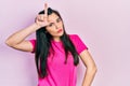 Young hispanic girl wearing casual pink t shirt making fun of people with fingers on forehead doing loser gesture mocking and