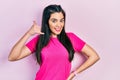 Young hispanic girl wearing casual pink t shirt smiling doing phone gesture with hand and fingers like talking on the telephone Royalty Free Stock Photo