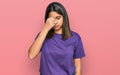 Young hispanic girl wearing casual purple t shirt tired rubbing nose and eyes feeling fatigue and headache