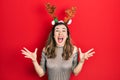 Young hispanic girl wearing deer christmas hat celebrating mad and crazy for success with arms raised and closed eyes screaming Royalty Free Stock Photo