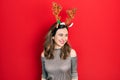 Young hispanic girl wearing deer christmas hat looking away to side with smile on face, natural expression Royalty Free Stock Photo