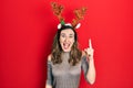 Young hispanic girl wearing deer christmas hat pointing finger up with successful idea Royalty Free Stock Photo