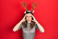 Young hispanic girl wearing deer christmas hat suffering from headache desperate and stressed because pain and migraine Royalty Free Stock Photo