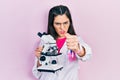 Young hispanic girl wearing scientist uniform holding microscope annoyed and frustrated shouting with anger, yelling crazy with Royalty Free Stock Photo