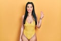 Young hispanic girl wearing swimsuit showing and pointing up with fingers number four while smiling confident and happy Royalty Free Stock Photo