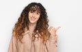 Young hispanic girl wearing winter clothes smiling with happy face looking and pointing to the side with thumb up Royalty Free Stock Photo