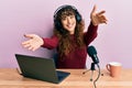 Young hispanic girl working at radio office looking at the camera smiling with open arms for hug Royalty Free Stock Photo