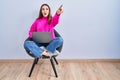 Young hispanic girl working using computer laptop pointing with finger surprised ahead, open mouth amazed expression, something on Royalty Free Stock Photo