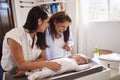 Young Hispanic grandmother and adult daughter playing with her baby son on changing table, waist up