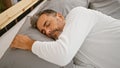 Young hispanic grey-haired man lying on bed sleeping at bedroom Royalty Free Stock Photo