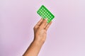 Young hispanic hand holding birth control pills over isolated pink background Royalty Free Stock Photo