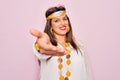 Young hispanic hippie woman wearing fashion boho style and sunglasses over pink background smiling cheerful offering palm hand Royalty Free Stock Photo