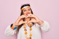 Young hispanic hippie woman wearing fashion boho style and sunglasses over pink background smiling in love doing heart symbol Royalty Free Stock Photo