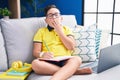 Young hispanic kid doing homework sitting on the sofa bored yawning tired covering mouth with hand Royalty Free Stock Photo
