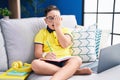 Young hispanic kid doing homework sitting on the sofa yawning tired covering half face, eye and mouth with hand Royalty Free Stock Photo