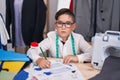 Young hispanic kid at tailor room thinking attitude and sober expression looking self confident Royalty Free Stock Photo