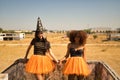 Young Hispanic and Latina women holding hands, smiling and leaning against a stone wall dressed for Halloween outside Royalty Free Stock Photo