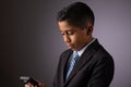 Young Hispanic Little Boy Looking at Phone. Dressed Neatly in a Suit Royalty Free Stock Photo