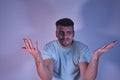 Young Hispanic male with hands up with gesture of doubt or question on white background