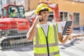 Young hispanic man architect talking on smartphone using touchpad at park Royalty Free Stock Photo