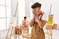Young hispanic man at art studio with sad expression covering face with hands while crying Royalty Free Stock Photo