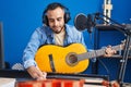 Young hispanic man artist composing song playing classical guitar at music studio Royalty Free Stock Photo
