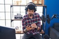 Young hispanic man artist listening to music composing song at music studio Royalty Free Stock Photo
