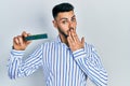 Young hispanic man with beard holding memory ram covering mouth with hand, shocked and afraid for mistake Royalty Free Stock Photo