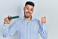 Young hispanic man with beard holding memory ram pointing thumb up to the side smiling happy with open mouth Royalty Free Stock Photo