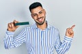 Young hispanic man with beard holding memory ram smiling happy pointing with hand and finger to the side Royalty Free Stock Photo