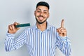 Young hispanic man with beard holding memory ram smiling with an idea or question pointing finger with happy face, number one Royalty Free Stock Photo