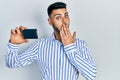 Young hispanic man with beard holding ssd memory covering mouth with hand, shocked and afraid for mistake Royalty Free Stock Photo