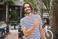Young hispanic man with beard outdoors at the city cheerful with a smile of face pointing with hand and finger up to the side with Royalty Free Stock Photo