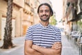 Young hispanic man with beard outdoors at the city happy face smiling with crossed arms looking at the camera Royalty Free Stock Photo