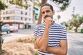 Young hispanic man with beard outdoors at the city looking confident at the camera with smile with crossed arms and hand raised on Royalty Free Stock Photo