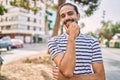 Young hispanic man with beard outdoors at the city looking confident at the camera smiling with crossed arms and hand raised on Royalty Free Stock Photo