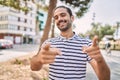 Young hispanic man with beard outdoors at the city pointing fingers to camera with happy and funny face Royalty Free Stock Photo