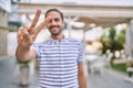 Young hispanic man with beard outdoors at the city smiling looking to the camera showing fingers doing victory sign Royalty Free Stock Photo