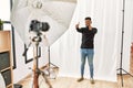 Young hispanic man with beard posing as model at photography studio approving doing positive gesture with hand, thumbs up smiling Royalty Free Stock Photo