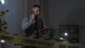 A young hispanic man with a beard speaks on the phone, reading notes in a crime scene indoor Royalty Free Stock Photo