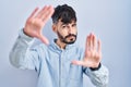 Young hispanic man with beard standing over blue background doing frame using hands palms and fingers, camera perspective Royalty Free Stock Photo