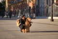 Young Hispanic man with beard, sunglasses, black shirt and backpack, crouched hugging his dog in the city. Concept animals, dogs, Royalty Free Stock Photo